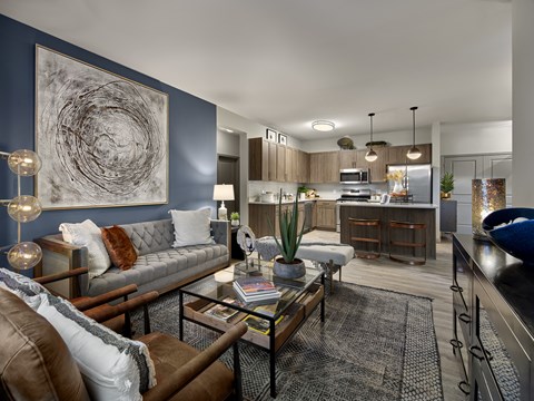 a living room with couches and a coffee table in front of a kitchen