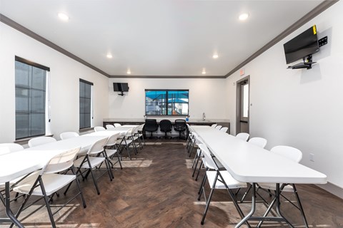 a conference room with white tables and chairs and a television