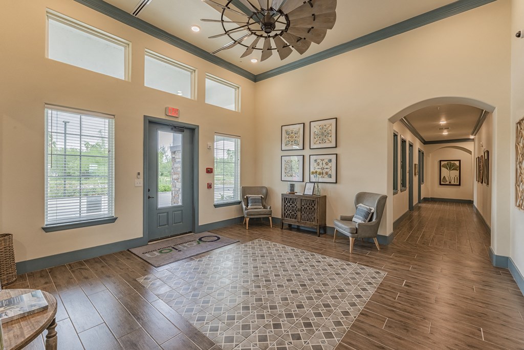 the lobby of a community center with chairs and a ceiling fan