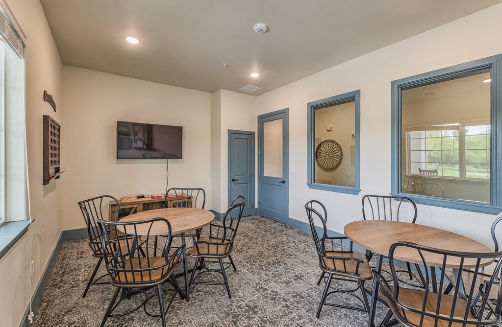 a community room with tables and chairs and a television