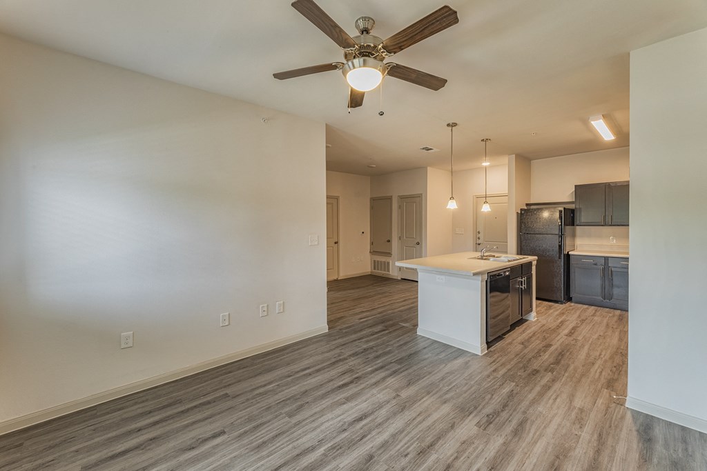 an empty living room and kitchen with a ceiling fan