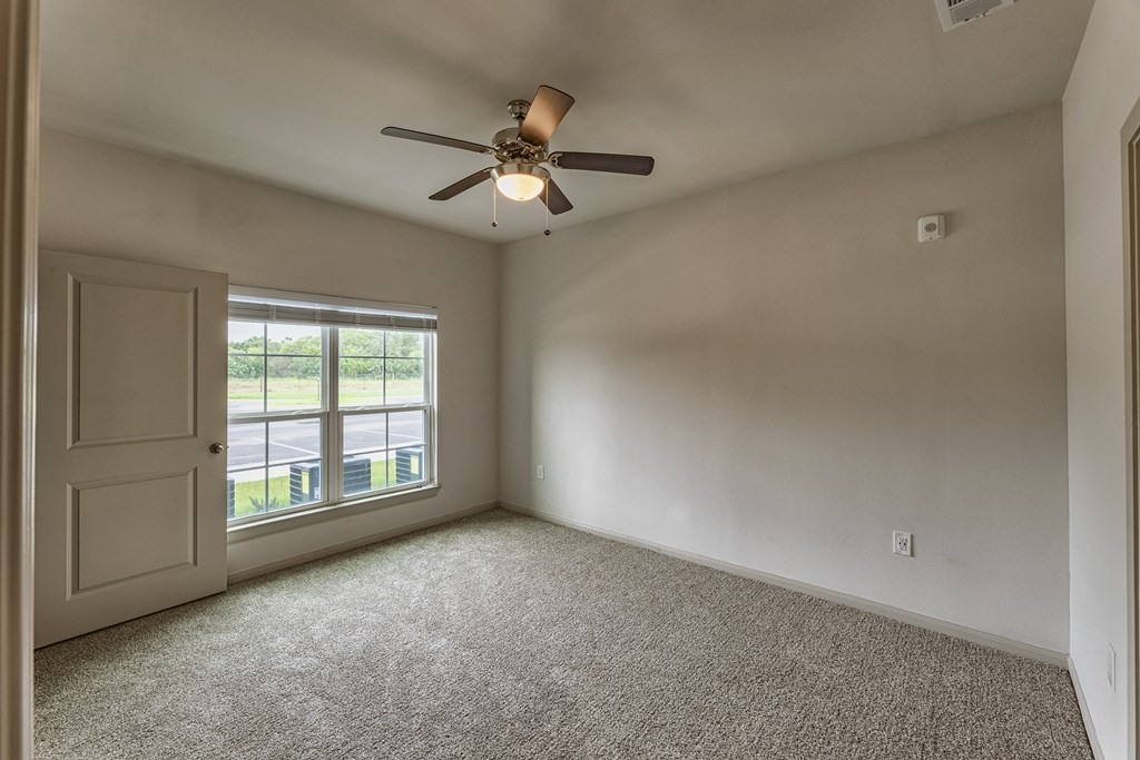 an empty living room with a ceiling fan and a window