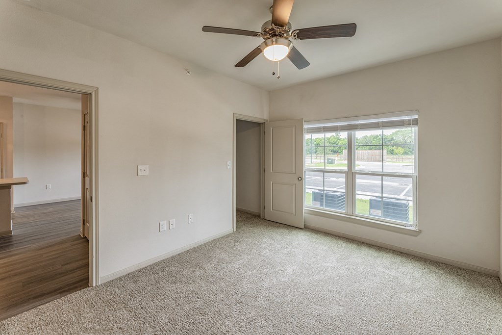 an empty living room with a ceiling fan and a window