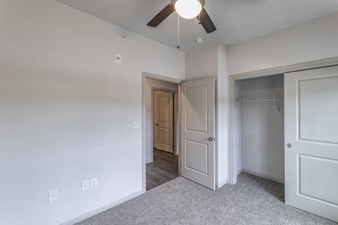 an empty bedroom with a ceiling fan and a closet