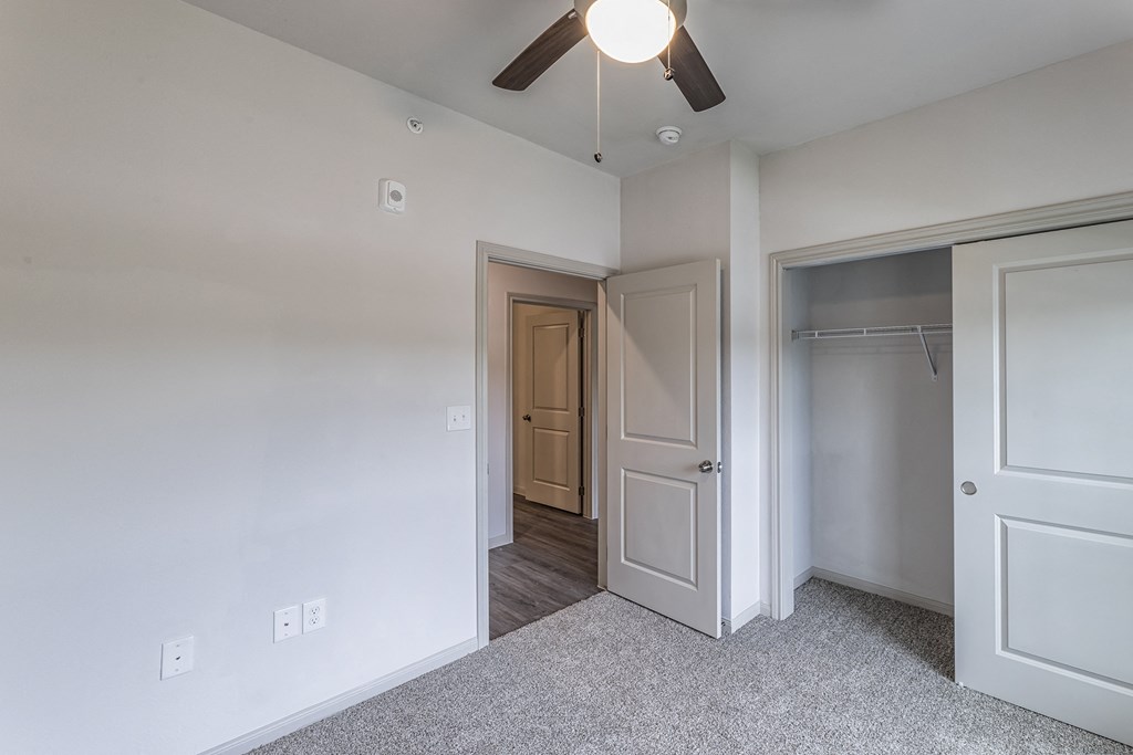 an empty bedroom with a ceiling fan and a closet