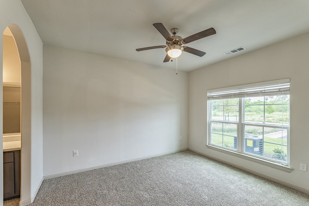 an empty living room with a ceiling fan and a large window