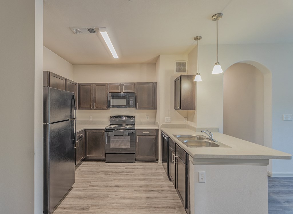 an empty kitchen with stainless steel appliances and a white counter top