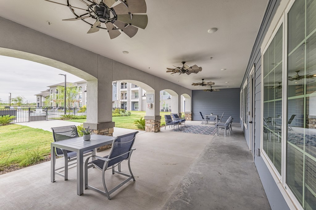 a covered patio with tables and chairs and a ceiling fan
