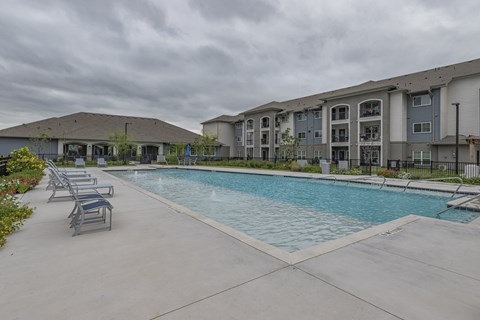 a swimming pool with chairs around it in front of a building