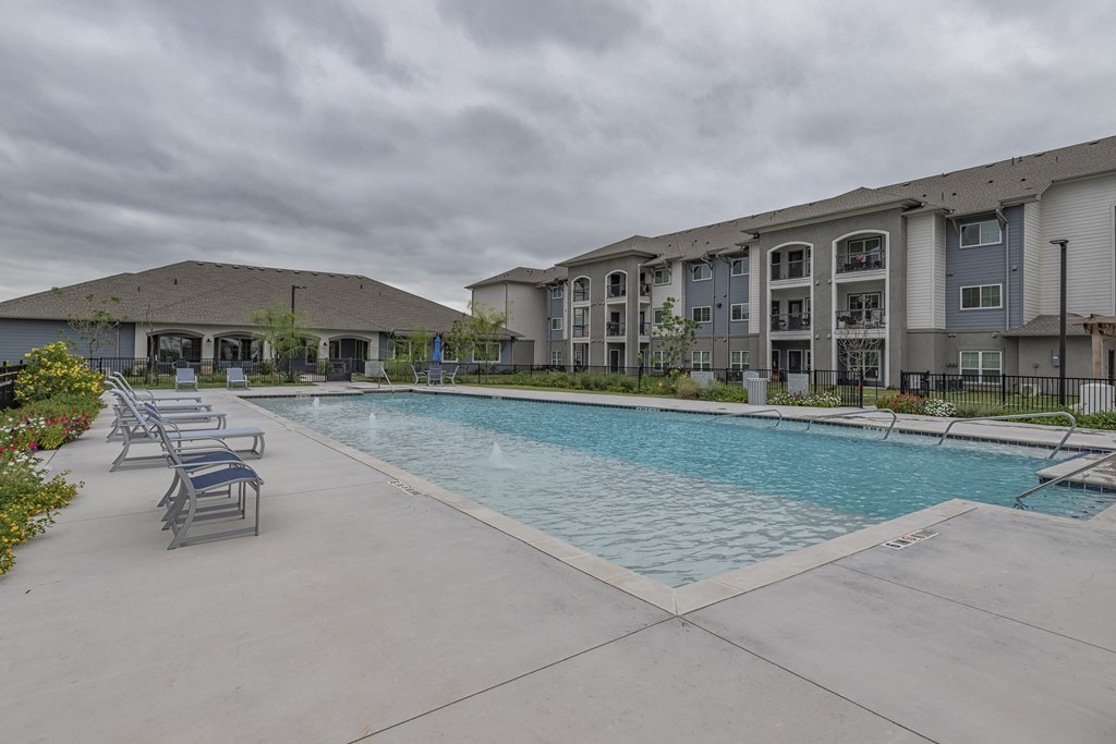 a swimming pool with chairs around it in front of a building