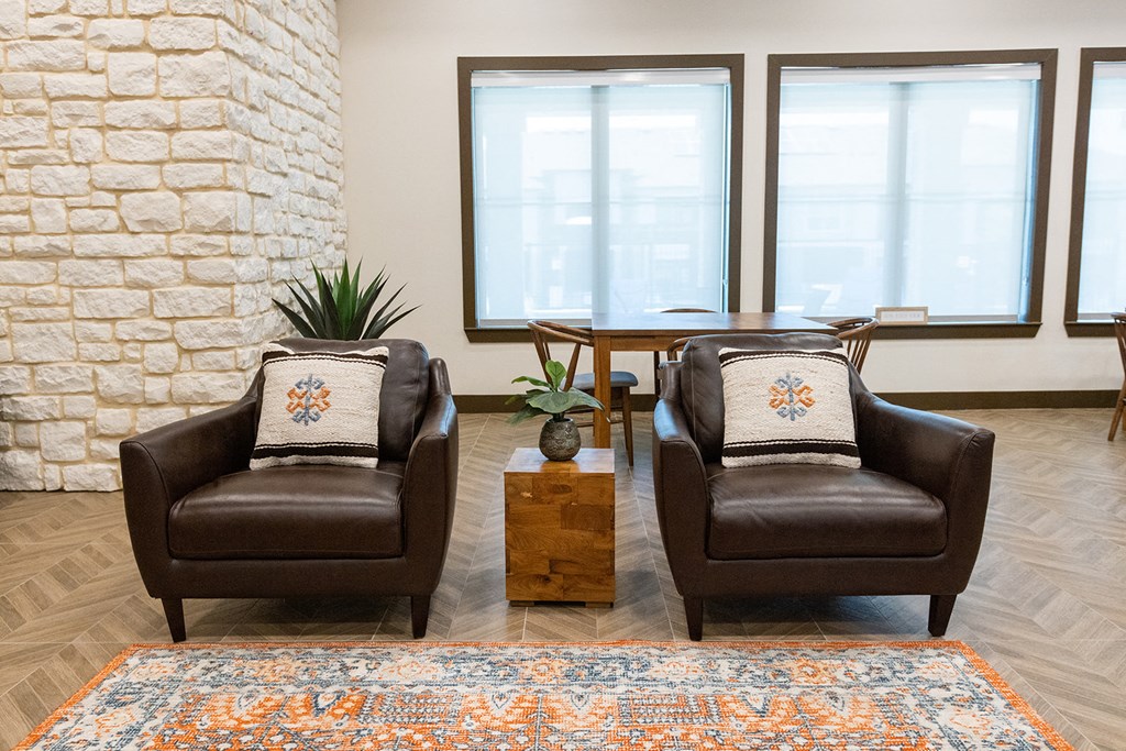 two leather chairs in a room with a table and windows
