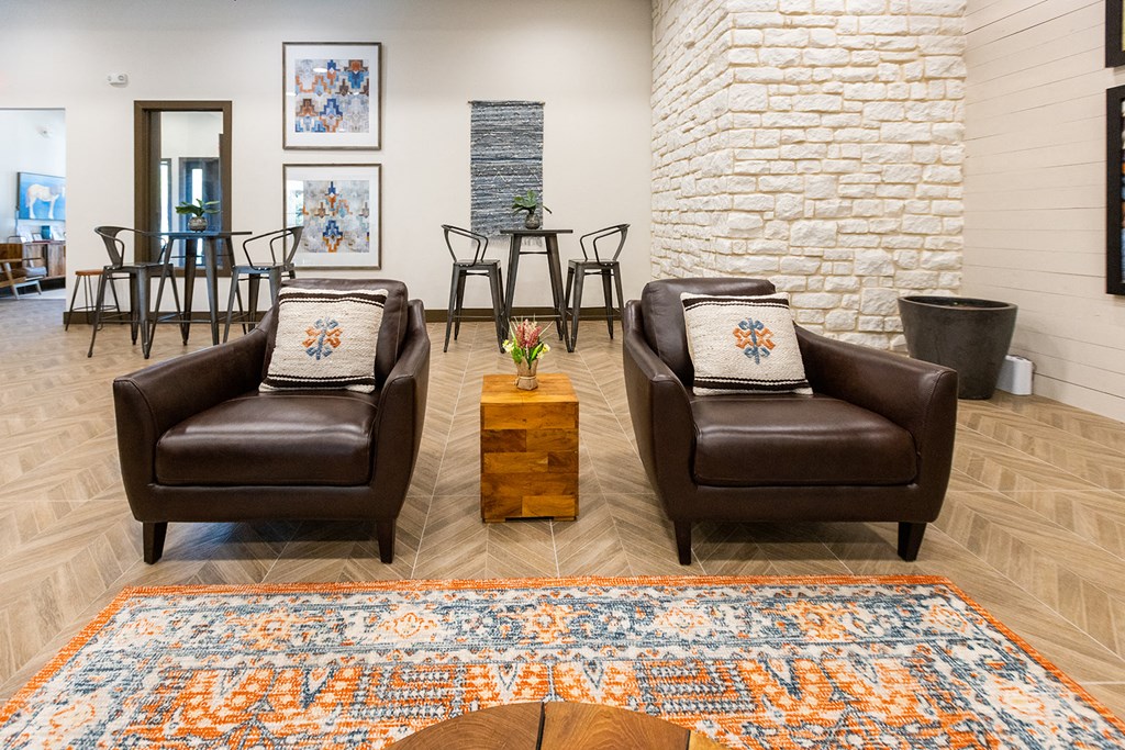a living room with two leather chairs and a rug and a dining room table