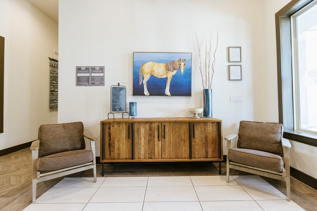 a living room with two chairs and a cabinet and a horse on the wall