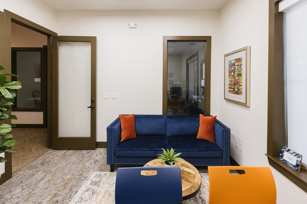 a living room with a blue couch and orange pillows