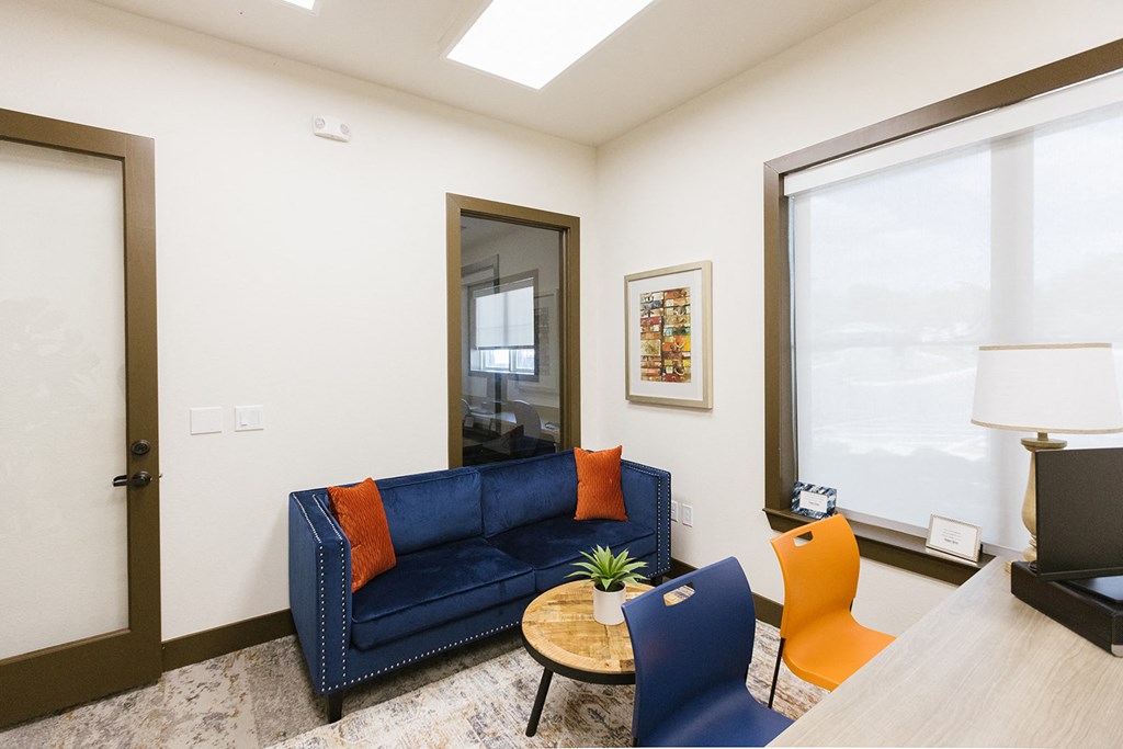 a living room with a blue couch and two chairs and a window