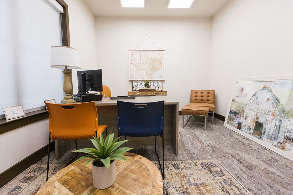 an office with a desk and chairs and a large window