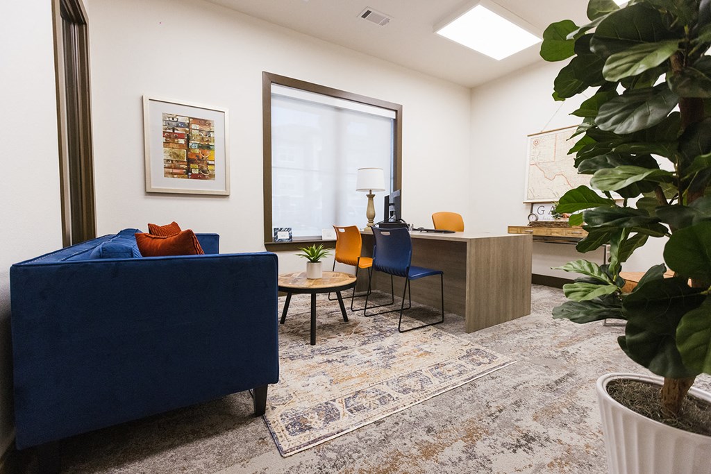 a living room with a blue couch and chairs and a desk