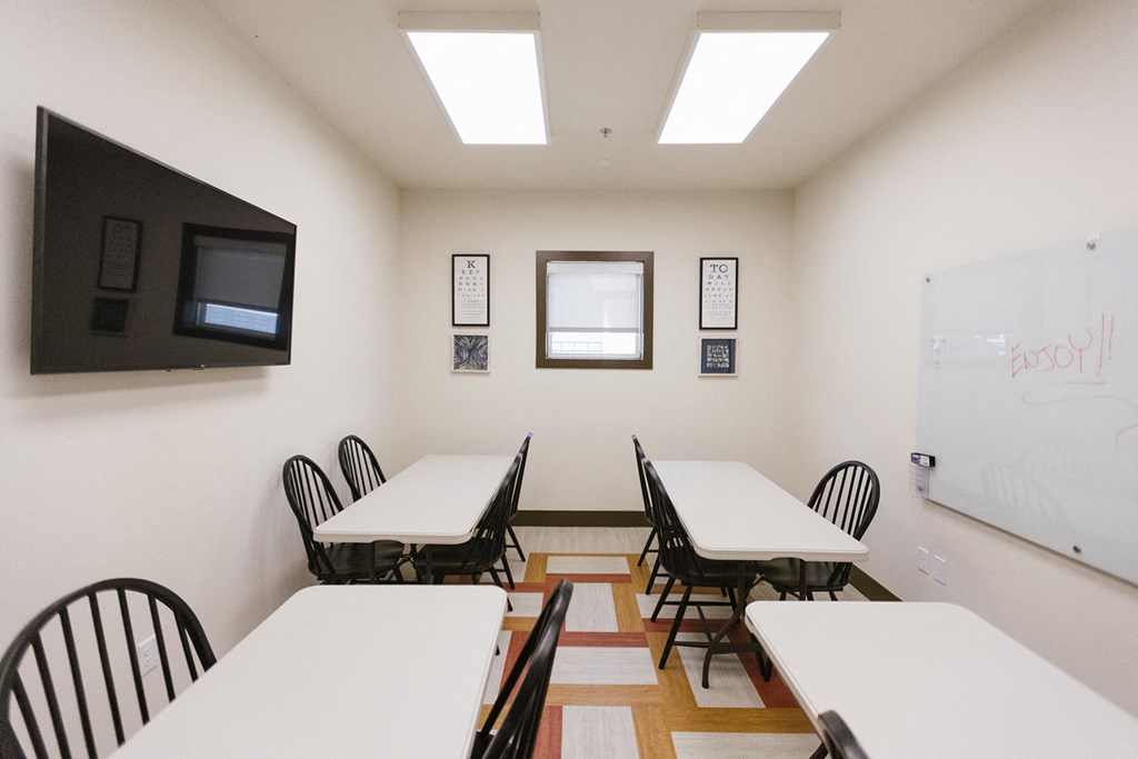 a classroom with tables and chairs and a whiteboard