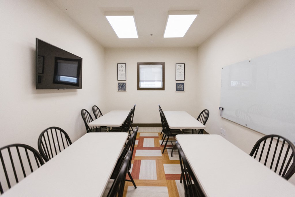 a conference room with tables and chairs and a television