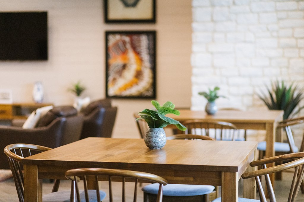 a wooden table and chairs in a restaurant with a plant on it
