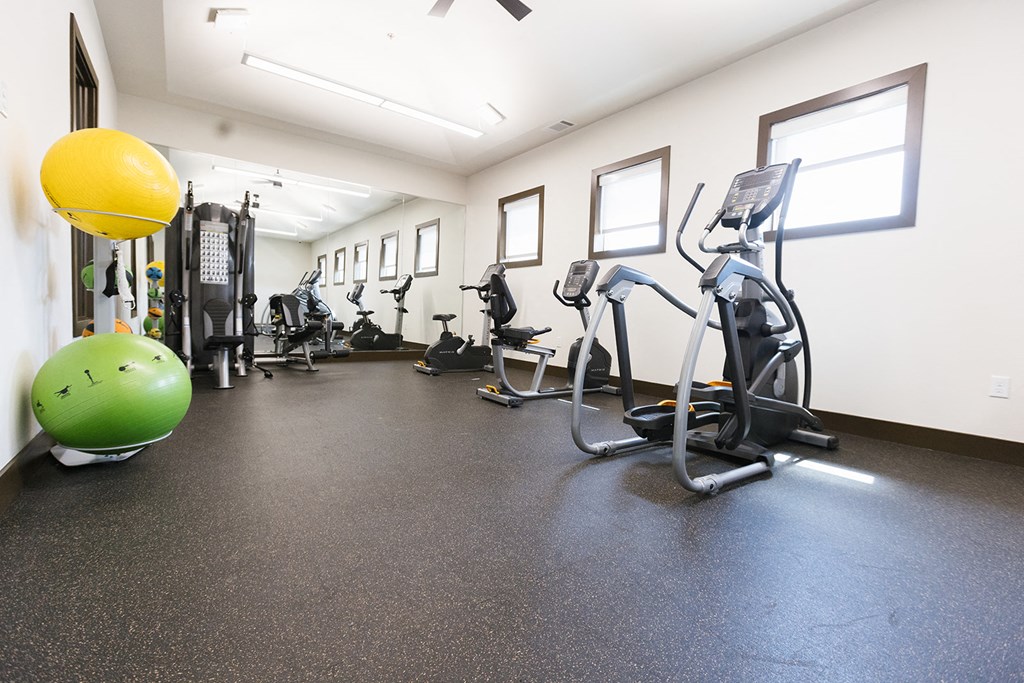 a gym with cardio equipment and weights on the floor