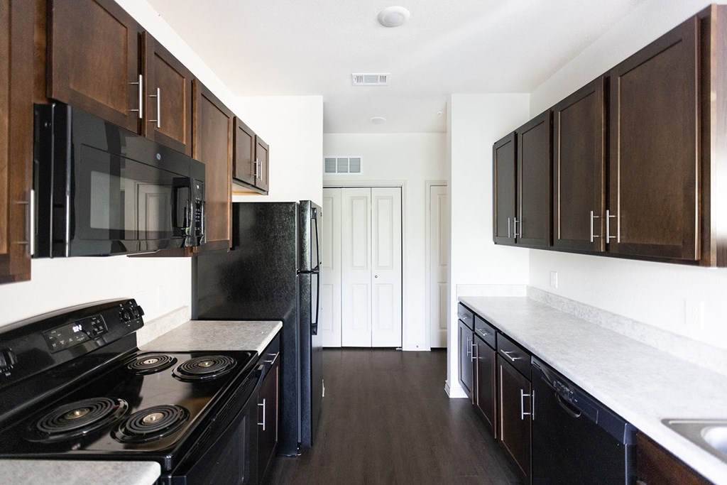 a kitchen with black appliances and wooden cabinets and white counter tops