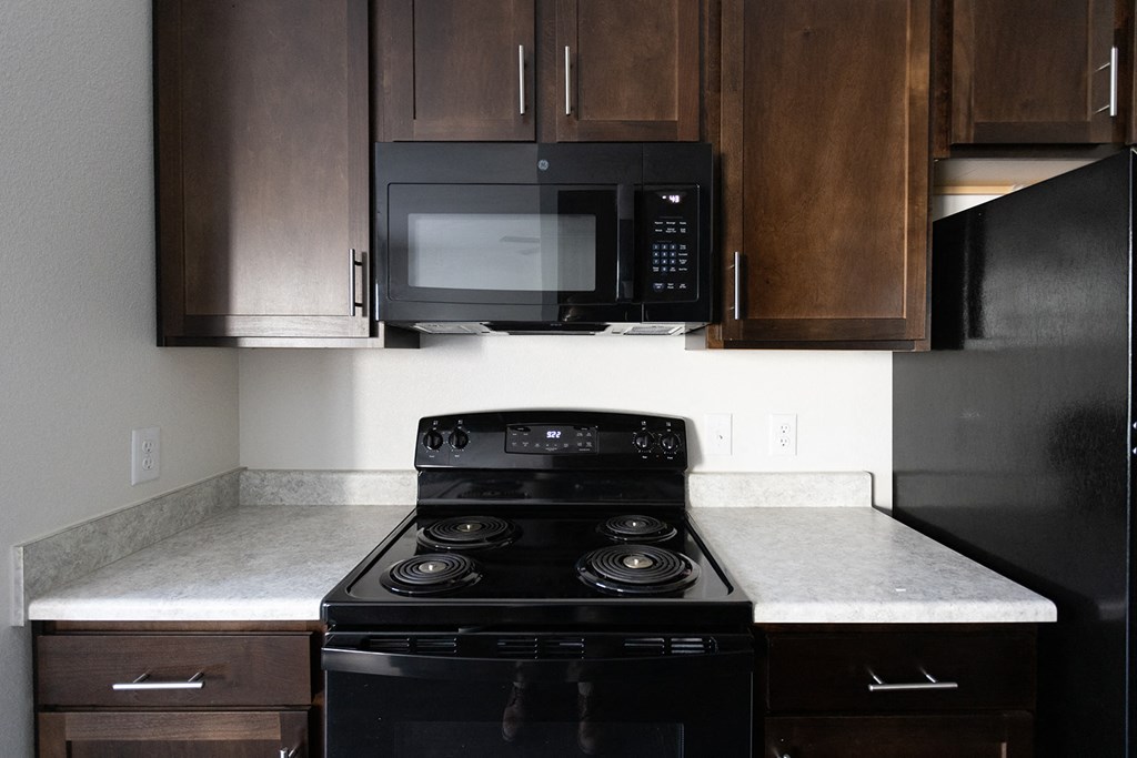 a kitchen with a stove and microwave and wooden cabinets