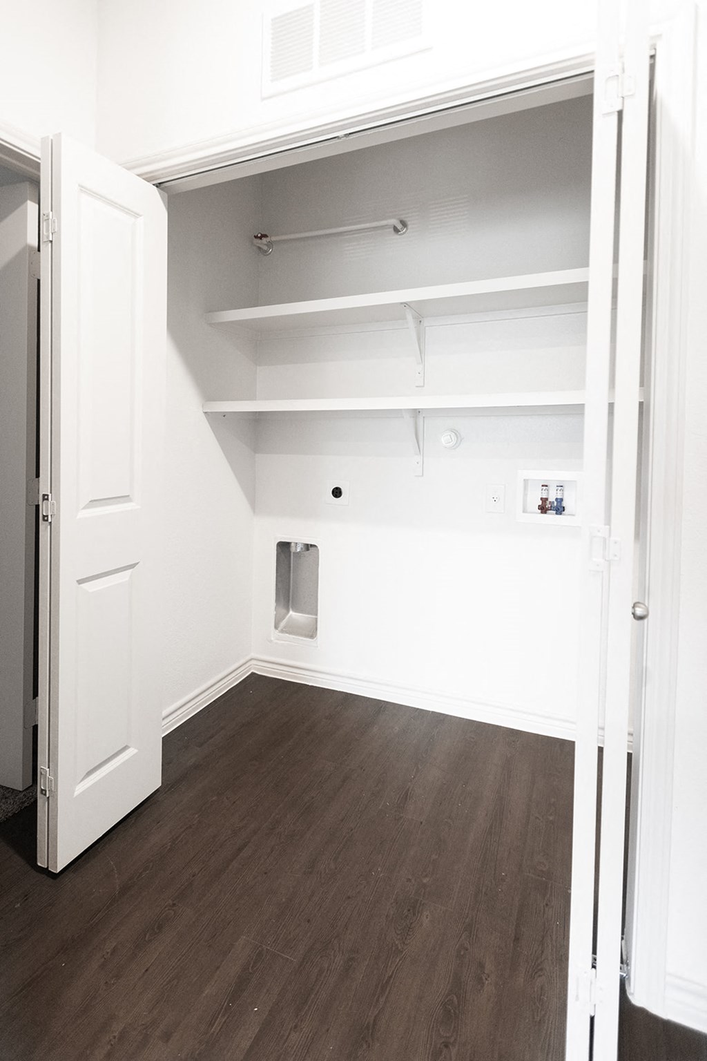 a bedroom with white walls and wood floors and a closet