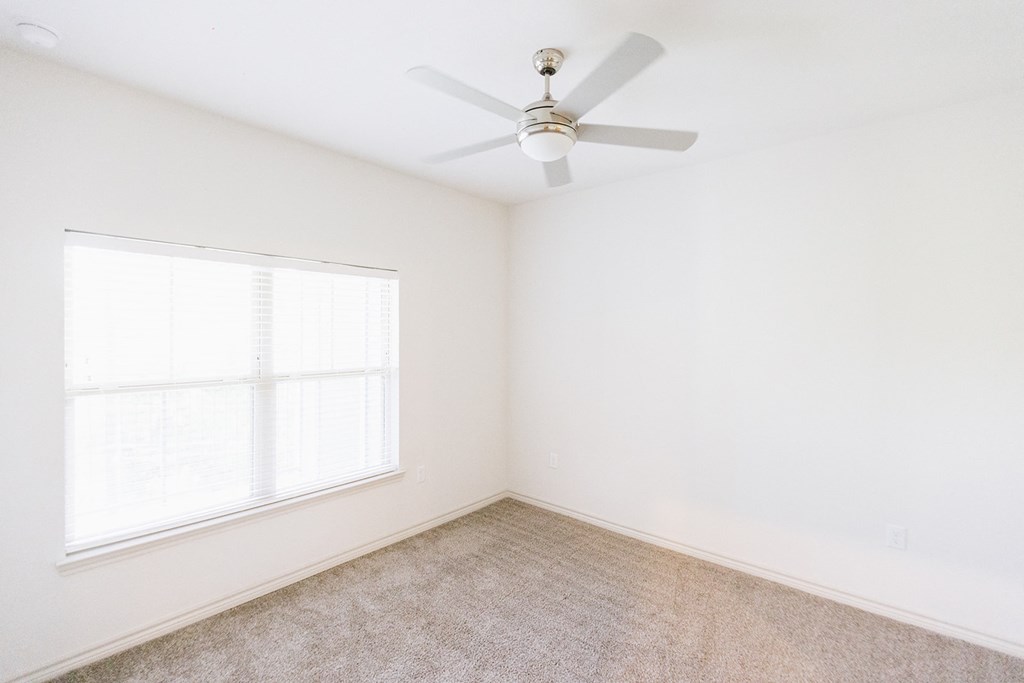 an empty room with a ceiling fan and a window