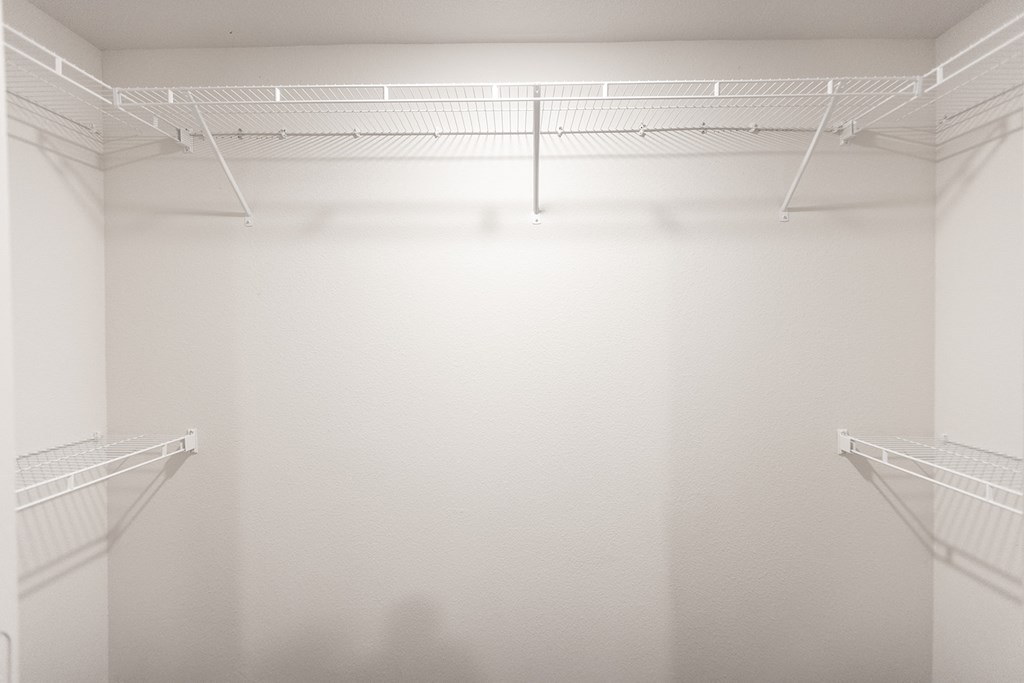 an empty closet with two shelves and a white wall