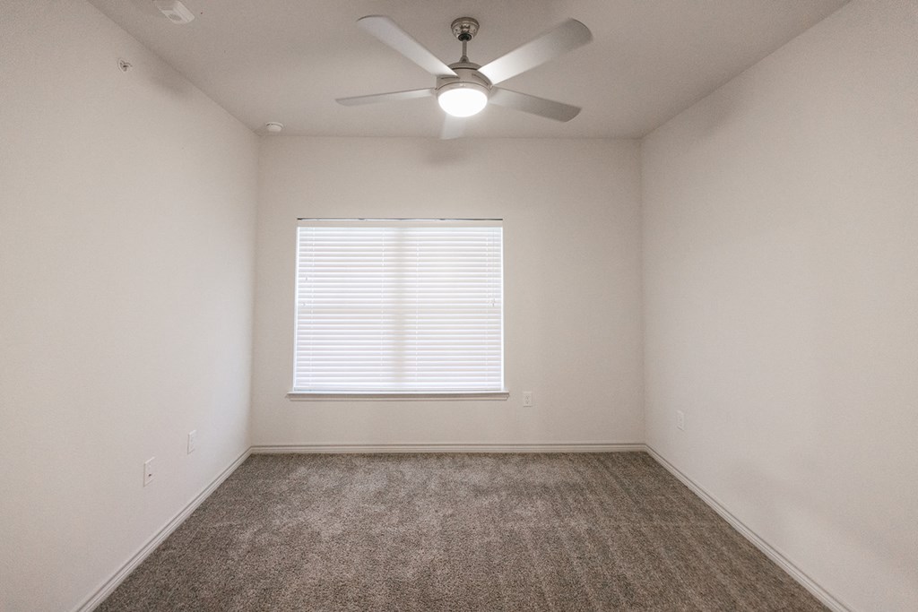 an empty room with a ceiling fan and a window