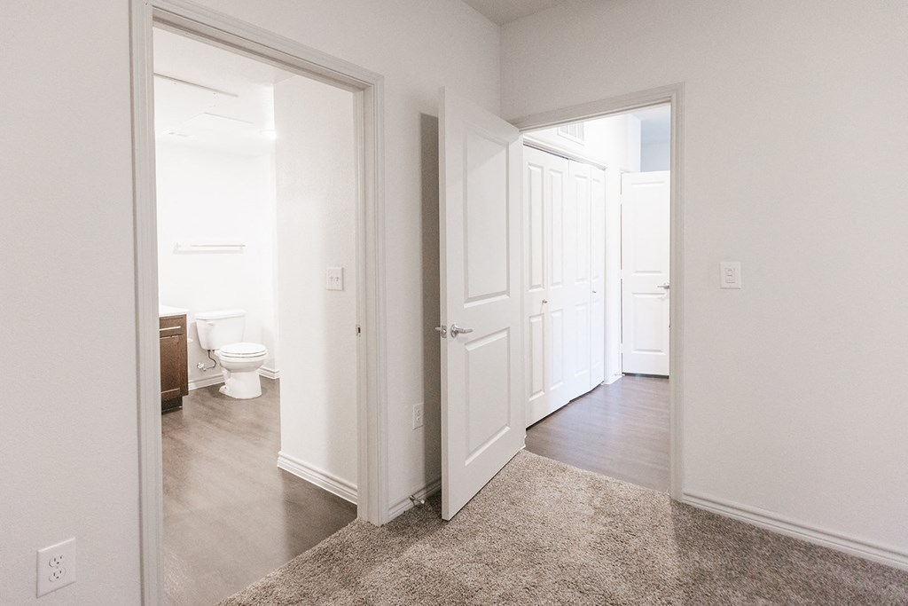 an empty hallway with a door open to a bathroom and a toilet