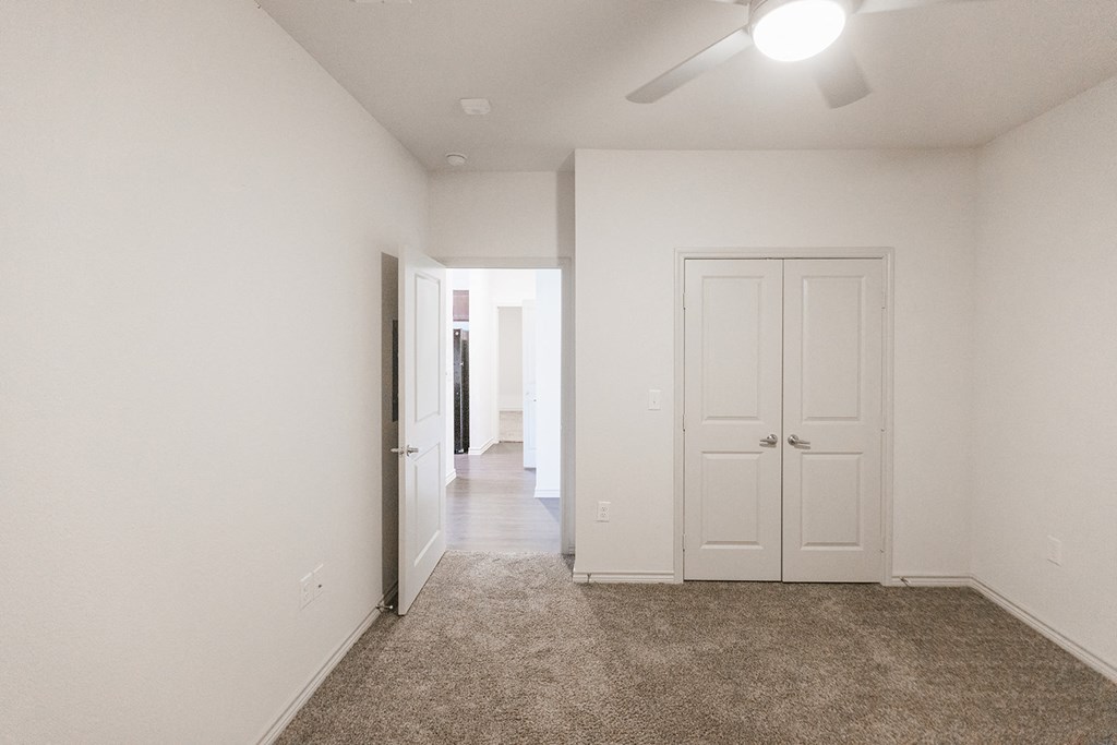 an empty room with a carpeted hallway and a white door