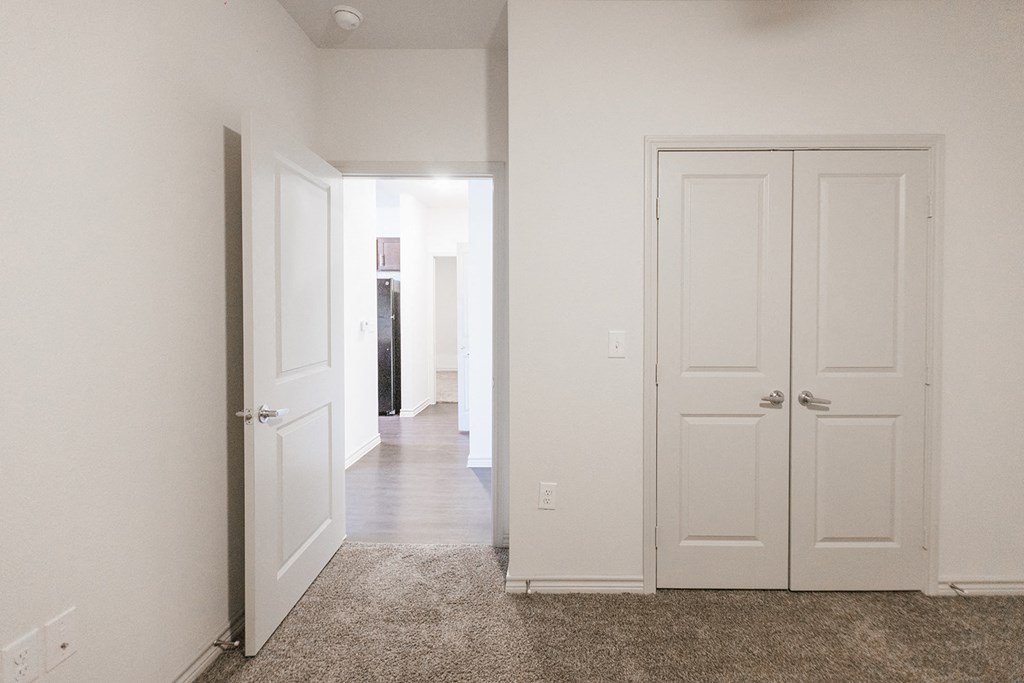 an empty hallway with white doors and a carpeted floor