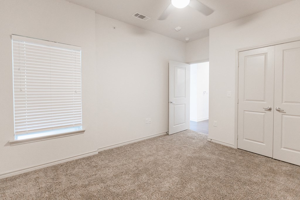 an empty bedroom with white doors and a carpeted floor