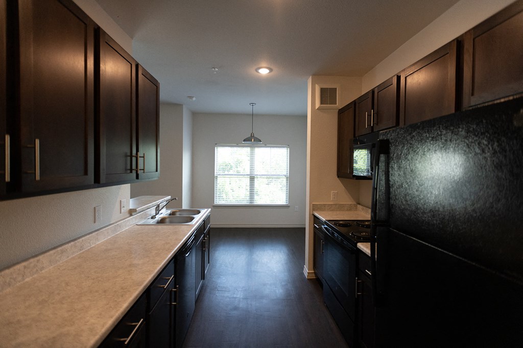 an empty kitchen with black appliances and dark wood cabinets