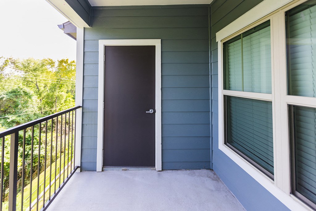 front door of a blue house with a black door knob and a balcony