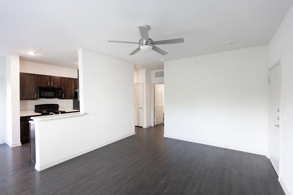 an empty living room with white walls and a ceiling fan