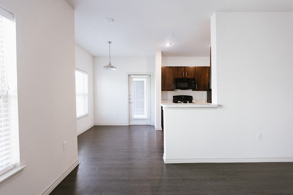 an empty living room with white walls and a kitchen