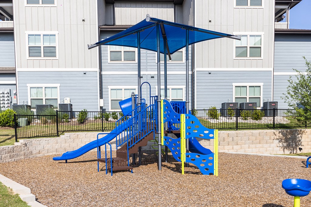 a blue playground with a slide and swing set in front of a building