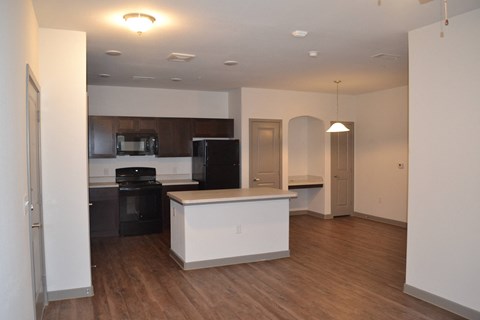 an empty kitchen and living room with wood floors and white walls