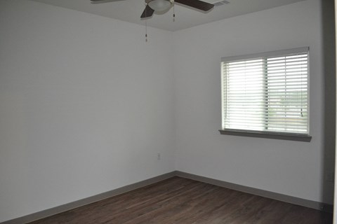 an empty room with a ceiling fan and a window