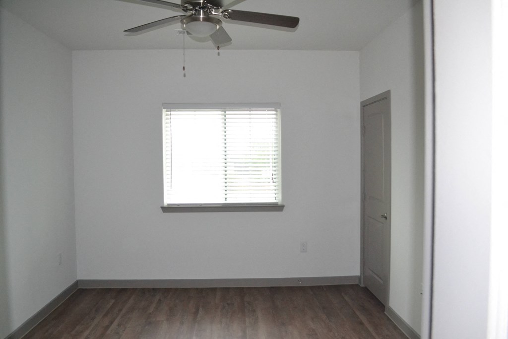 an empty room with a ceiling fan and a window
