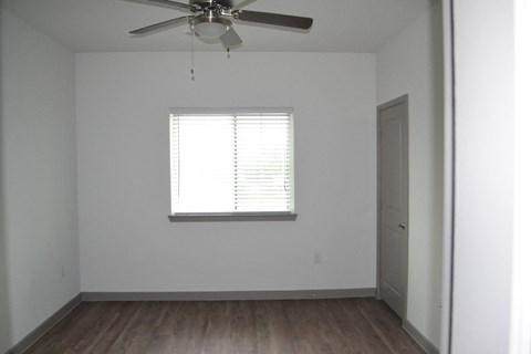 an empty room with a ceiling fan and a window
