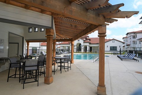 the clubhouse has a large patio with tables and chairs and a pool
