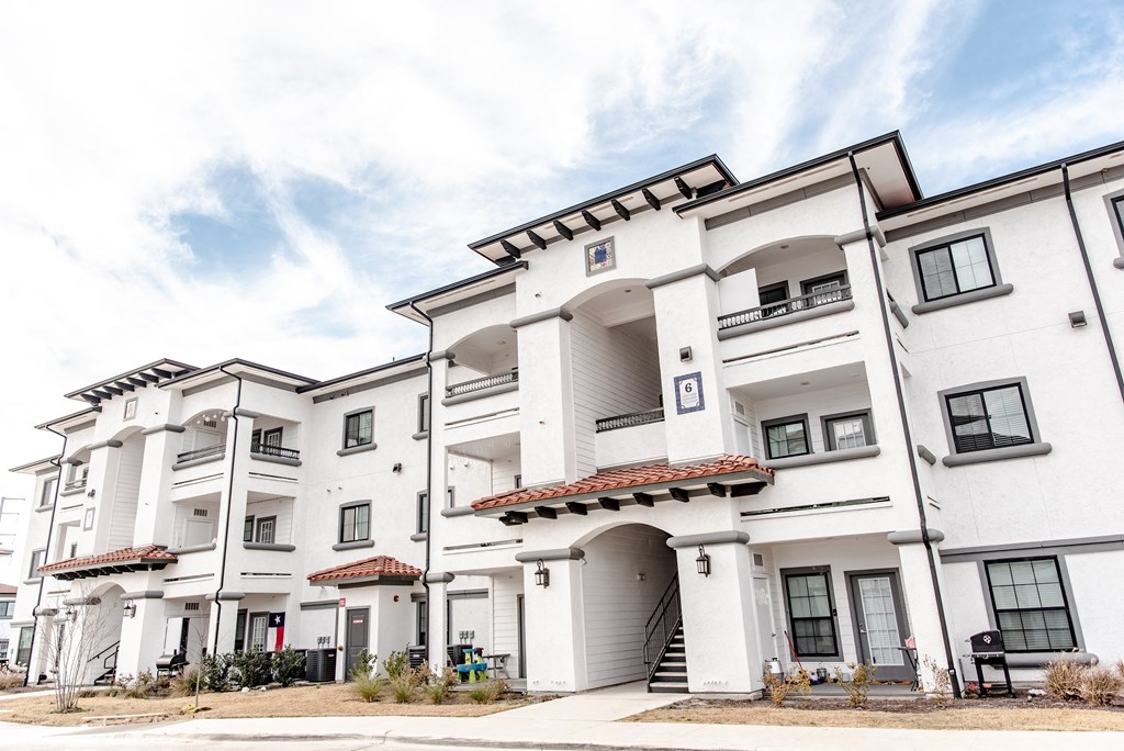 a group of white apartment buildings with a blue sky in the background