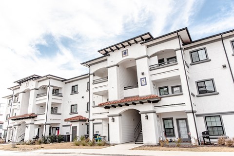 a group of white apartment buildings with a blue sky in the background