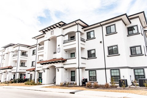 a group of white apartment buildings with a street in front