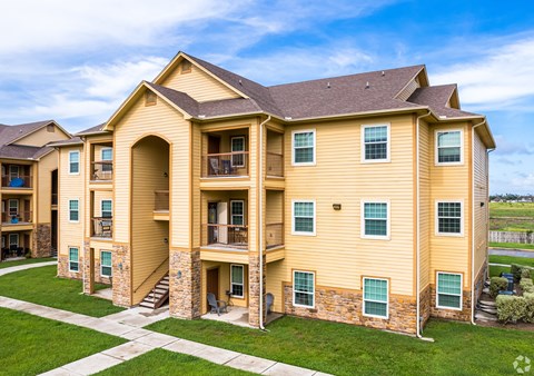 A large, two-story apartment building with a mix of balconies and patios.