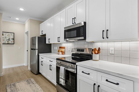 A kitchen with white cabinets and black appliances.